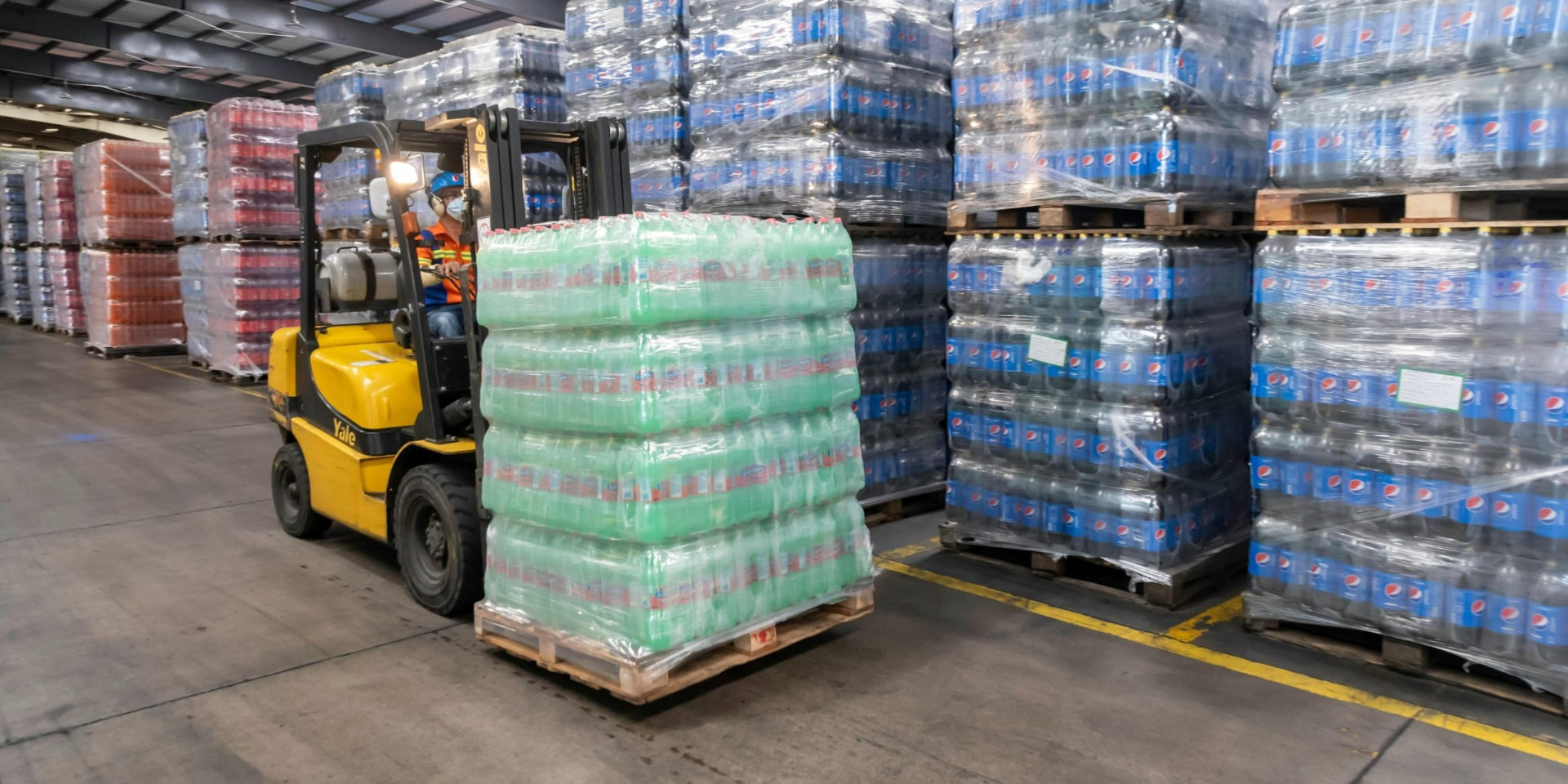 Motostivuitor cu paleți de băuturi într-un depozit de distribuție